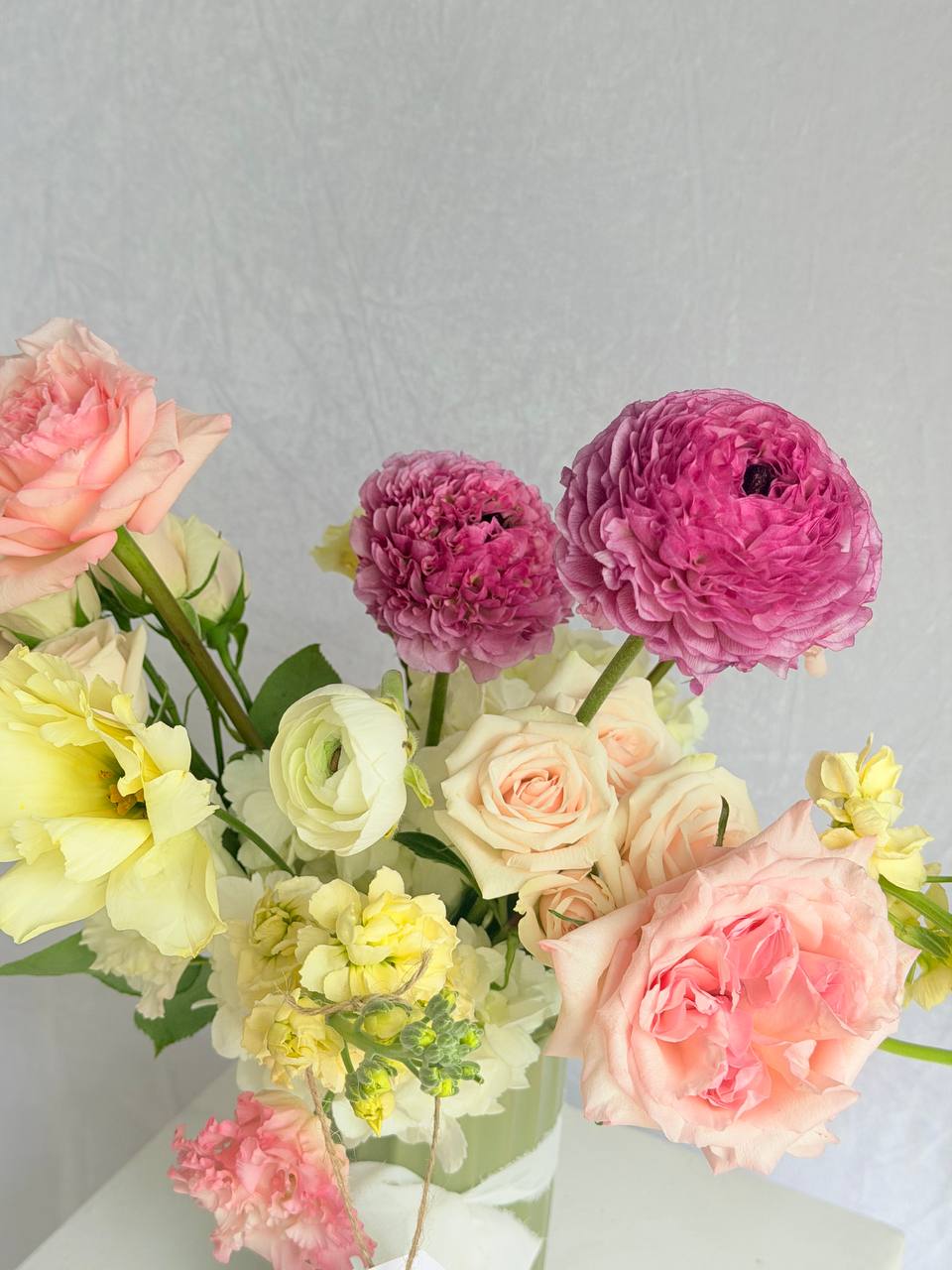 Bouquet of pink, yellow, and white flowers on a light gray background