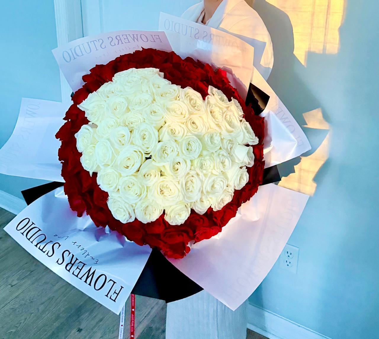 Bouquet of red and white roses with 'Flowers Studio' branding.