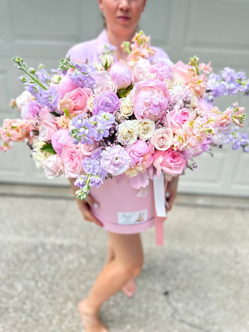 Person holding a large bouquet of pastel flowers against a neutral background