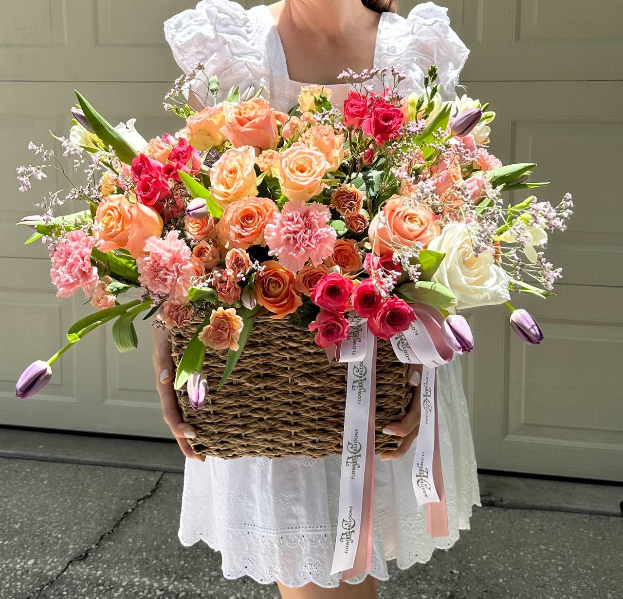 Person holding a large, colorful bouquet of flowers in front of a neutral background