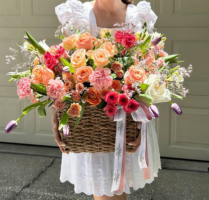 Person holding a large, colorful bouquet of flowers in front of a neutral background