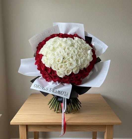 Bouquet of red and white roses on a wooden table with a plain background
