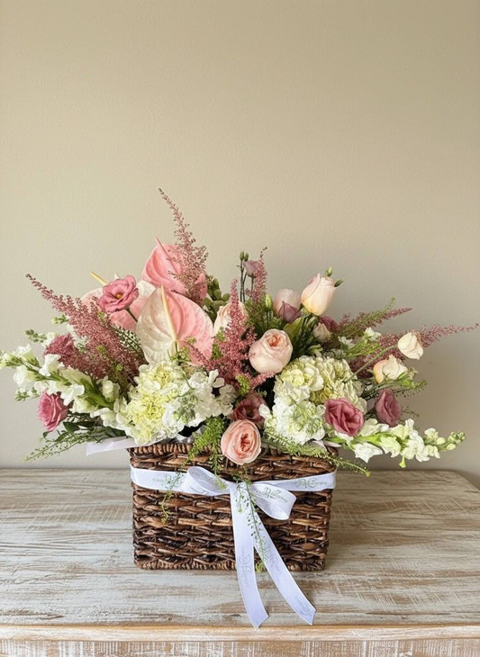Floral arrangement in a woven basket on a wooden surface with a neutral background