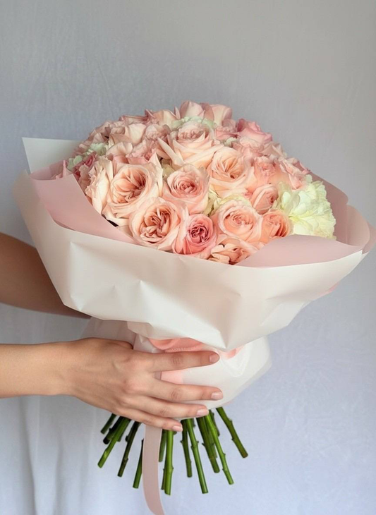 Bouquet of pink and white roses held by hands against a light background