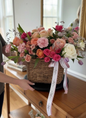 Bouquet of flowers in a woven basket on a wooden surface with a blurred background
