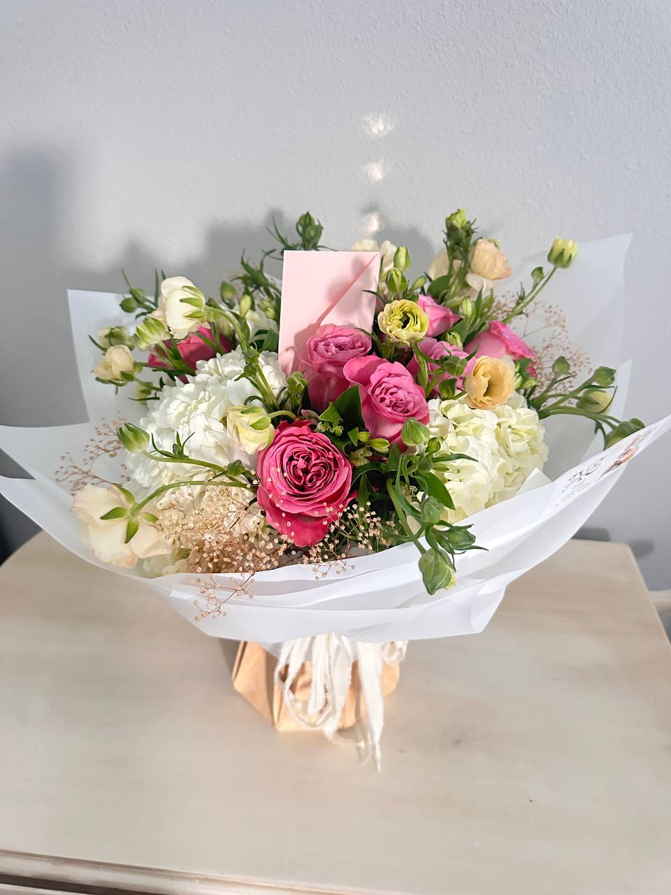 Bouquet of flowers with a pink box on a light surface