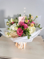 Bouquet of flowers with a pink box on a light surface